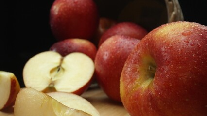 Macrography, slices of fresh apple are arranged on a cutting board against a striking black background. Each close-up shot captures the crisp texture and vibrant colors of the apples. Comestible.