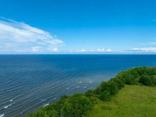 Aerial view of calm and wild Saka beach with a clear blue water on a sunny summer day. Beautiful green field with trees and bushes near the sea. Saka, Ida Viru county, Estonia. 