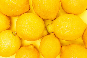 Close-up view of fresh lemons arranged on a vibrant yellow surface