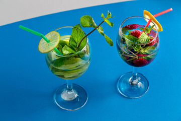 Two Glasses with fruit cocktail kiwi raspberry mint lime with ice on wooden table