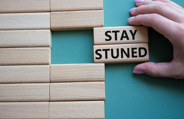 Stay Tuned symbol. Wooden blocks with words Stay Tuned Beautiful grey green background. Businessman hand. Business and Stay Tuned concept. Copy space.