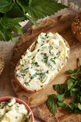 Nettle butter - homemade bread spread made of wild edible plants, on a slice of sourdough bread, top view