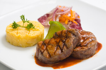Grilled beef steaks served with mashed potatoes and vegetables on white plate