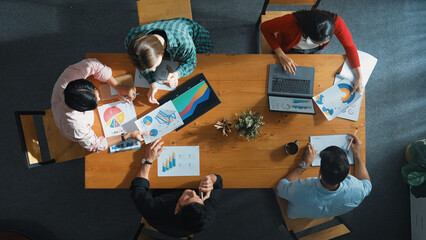 Top down view of manager holds tablet display increasing sales and placed on meeting table. Group of diverse business team clapping hands to celebrate successful product at meeting room Convocation.