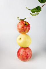 the balance of red and yellow apples and leaves on a white background