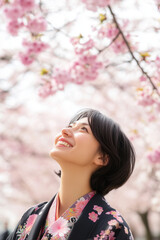 Fototapeta premium Young japanese woman in the park full of cherry tree walk and smile