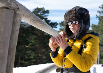 Caucasian boy eating a sandwich while spending a day in the snow wearing snow clothes