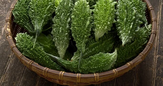 Homegrown bitter gourds (Momordica charantia)  in wicker bowl. Table spin.