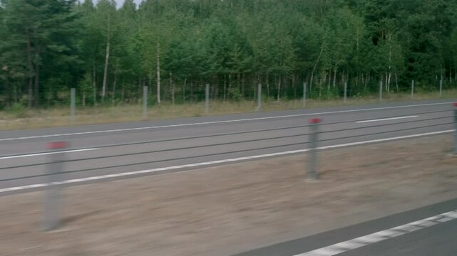 View of the road and forest from the window of a moving vehicle