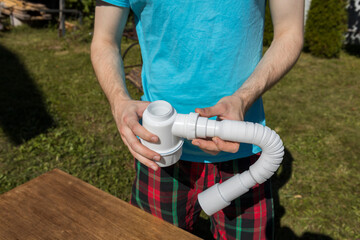 A man is holding a white hose in his hand