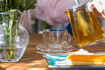 A person is pouring tea into a cup from a teapot