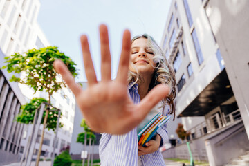 Teenage girl extends her palm towards the camera, high five, dynamic portrait, wide angle view from below