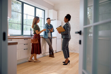 Happy black real estate agent and  couple in the kitchen of  new house.