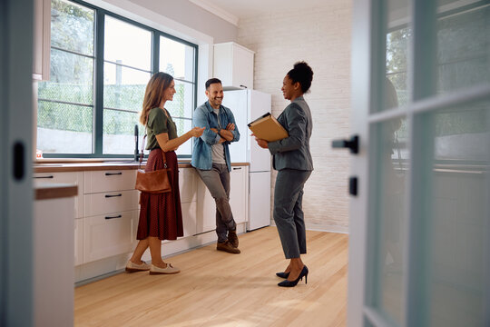 Happy black real estate agent and  couple in the kitchen of  new house.