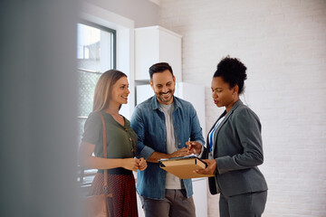 Happy couple and real estate agent going through lease agreement.