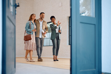 Happy African American real estate agent showing  house for sale to couple interested in buying it....