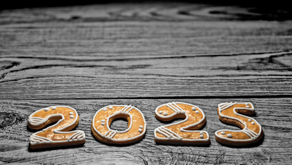Closeup of golden baked gingerbreads for 2025 happy New year greetings on dark wood. Beautiful...