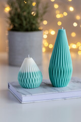 Handmade candles on a table with plant in a pot and lights in background. Home decor.