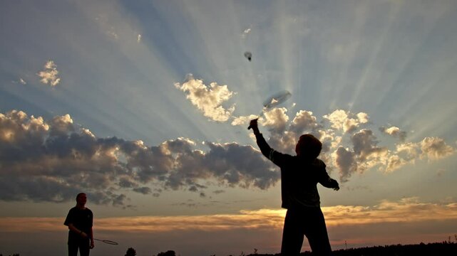 boy and girl playing badminton on sunset background. happy family concept