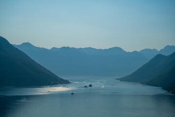 Serene mountain bay at dusk with distant boats. Montenegro, Bay of Kotor