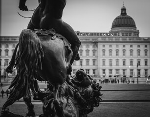 Statue of the Löwenkämpfer (lion fighter) outside the Altes Museum in Berlin, Germany. The Berliner Schloss (Humboldt Forum) is visible in the background.