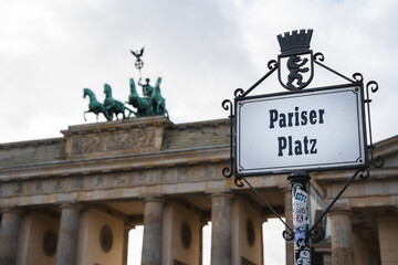 A street sign for Pariser Platz at Brandenburg Gate (Brandenburger Tor) in Berlin, Germany. The gate is visible in the background.