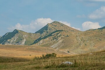 Grassy mountain slopes with rocky terrain under blue sky. Durmitor National Park Montenegro