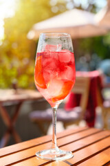 The glass of Aperol Spritz cocktail with ice cubes on the table in outdoors restaurant. Alcoholic beverage in sidewalk cafe.
