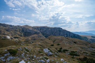 Rocky mountain cliffs and grassy slopes under cloudy sky. Durmitor National Park Montenegro