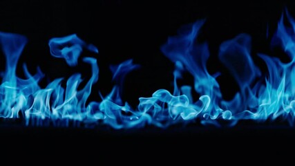 Gas burns with a bright blue flame. Blue fire is burning. Slow-motion video of bright blue flames against a black background. A wall of real fire with an abstract background. Super-slow motion video
