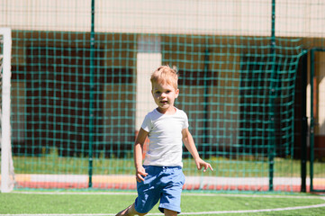 4 year old boy playing with a ball on a football field