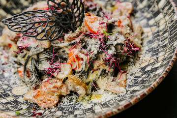 Gourmet black pasta with creamy sauce, cherry tomatoes, and decorative elements - Italian cuisine