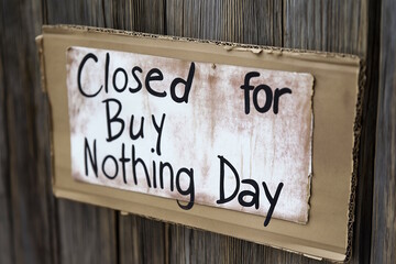 Sign reading "Closed for Buy Nothing Day" on a wooden door, promoting anti-consumerism. Concept of Buy Nothing Day and environmental awareness