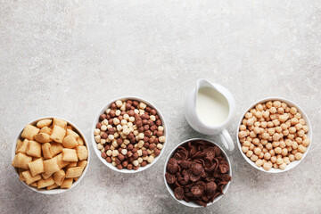 Various corn flakes with milk in jar on grey background