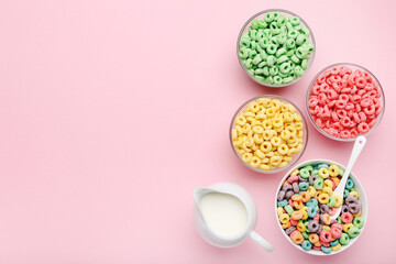 Colorful corn flakes with milk in jar and spoon on pink background