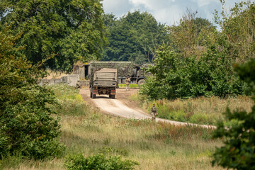 Naklejka premium a dark green army MAN SV 4x4 utility truck entering a camp