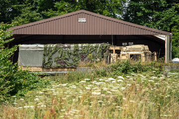 unloaded British army MAN HX77 8x8 EPLS Heavy Utility Truck in front of a large open fronted barn