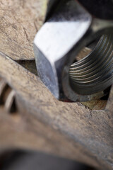 Adjustable wrench holding metal nut on dark background. Macro shot of tool and hardware for construction and repair.