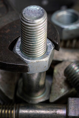 Wrench tightening metal bolt surrounded by nuts and bolts. Macro shot of construction and repair tools.