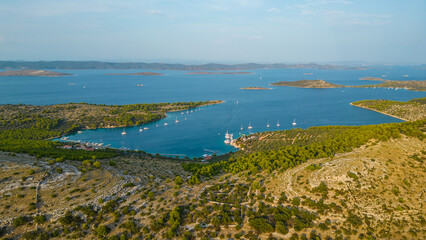 An aerial view of a serene bay on Otok Žut, located near the Kornati Islands in Croatia. The bay, surrounded by lush greenery and rocky shores, offers a tranquil retreat in the Adriatic Sea