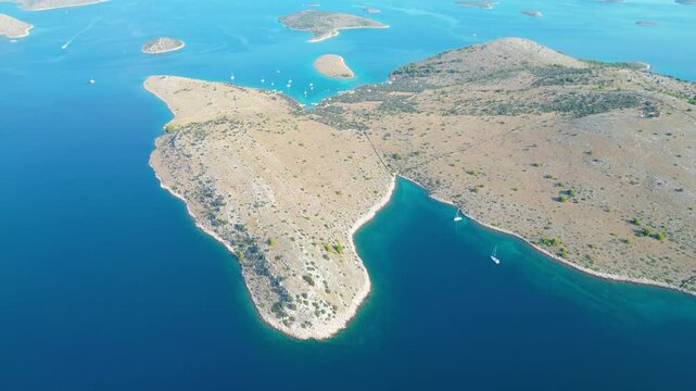 An aerial view of a serene bay on Otok Žut, located near the Kornati Islands in Croatia. The bay, surrounded by lush greenery and rocky shores, offers a tranquil retreat in the Adriatic Sea