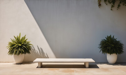 A white bench sits in front of a white wall with two potted plants on either side, casting shadows in the afternoon sun