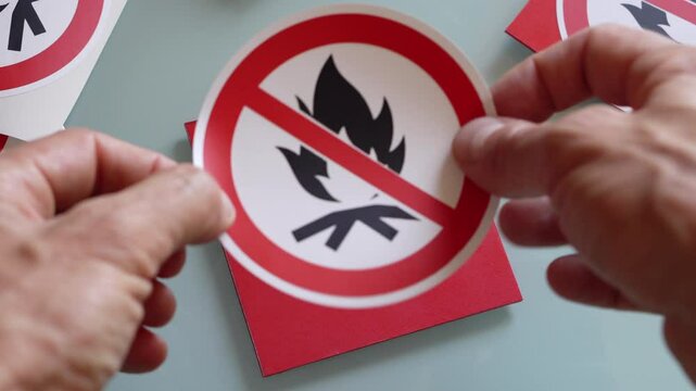 Placing  "no fire" sticker on a red  plastic board.