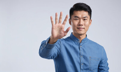 A man wearing a blue shirt holds up five fingers in front of a white background