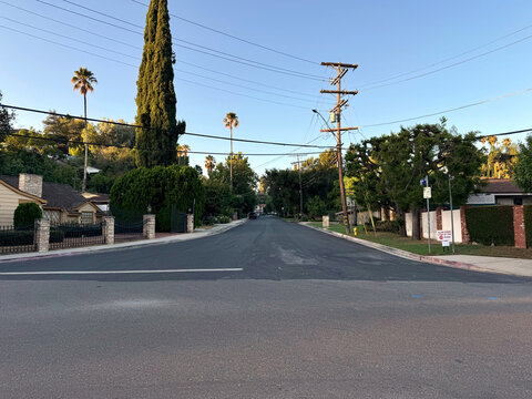 nice residential neighborhood street (big houses, parked cars, telephone poles, hedges, trees, street signs, gates, sidewalks) - Los Angeles, California - Powered by Adobe