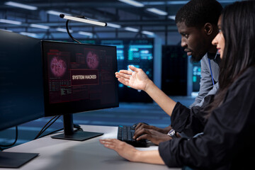 Programmers doing teamwork in server hub trying to protect hardware from hacker stealing information. Colleagues in data center workspace trying to fix security breach alert caused by virus