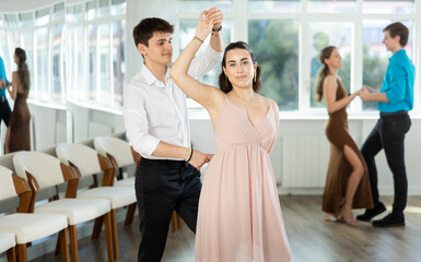 Couple of young guy and young woman dancing waltz in studio