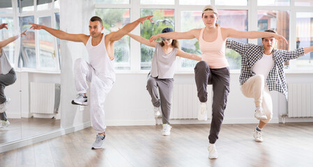 Fototapeta premium Young girl standing performs basic hip hop movements in front of group of students. Developing precise movements, rehearsing arc elements, nae nae moving