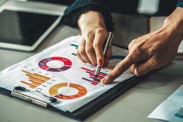 Businessman and businesswoman in meeting working with many financial statement document on desk. Concept of busy business profit analysis and brainstorm. Close up shot at people hands and papers. uds