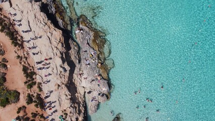People swimming in crystal clear turquoise sea water. Comino Island, Malta, Aerial top down view. High quality photo